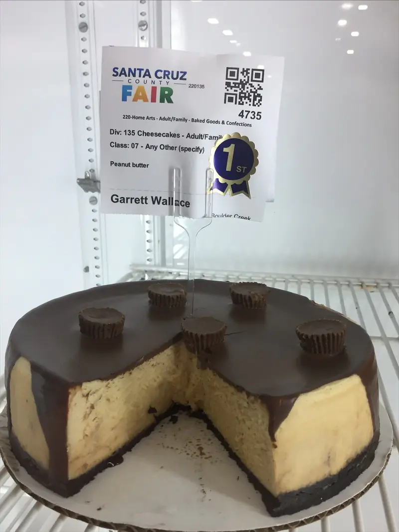 Garrett’s peanut butter cheesecake under a chocolate glaze with peanut butter cups on top, cut open, with a first-place sticker on its entry tag