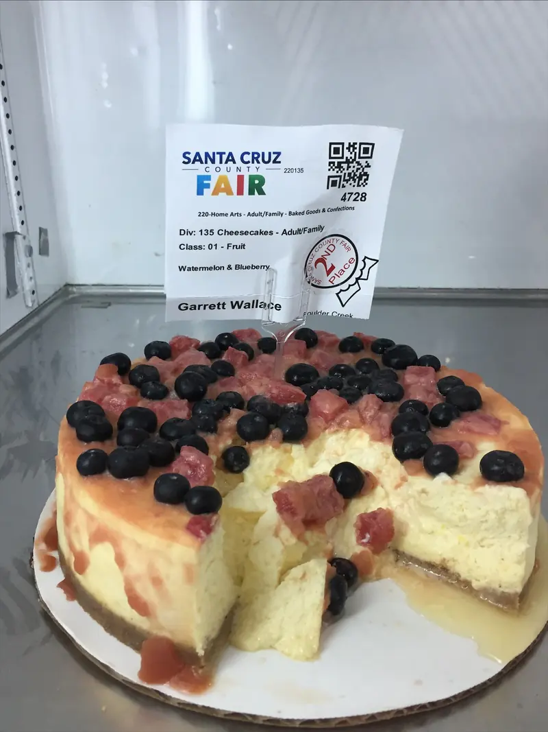 Garrett’s watermelon and blueberry cheesecake topped with blueberries and watermelon, cut open, with a second-place sticker on its entry tag